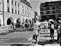 1996-12  8 czerwca 1996  Jawor, Rynek  II Półmaraton Jaworski o Puchar Burmistrza Jawora    Biegi towarzyszące dla dzieci i młodzieży  Sygnał gwizdkiem daje: Janusz Mazurek  W tle północno-zachodni fragment rynku i ulica Kościelna