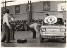 Wymiana koła w samochodzie fiat 126p podczas Turnieju Rodzin, zorganizowanego przy współpracy Obornickiego Ośrodka Kultury w hali sportowej OSiR, 20.03.1983 r. [Dokument ikonograficzny]