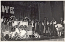 Scena zbiorowa z udziałem zespołu ludowego i kapeli na scenie Obornickiego Ośrodka Kultury podczas gminnych eliminacji Turnieju Kolorowe Wsie, 5.06.1983 r. [Dokument ikonograficzny]