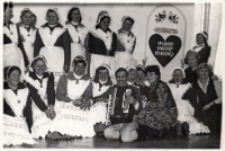 Zespół ludowy „Malwy” z Kuraszkowa w Muzeum Etnograficznym we Wrocławiu przy tablicy tytułowej wystawy „Wiano panny młodej na Śląsku”, 14.03.1984 r. [Dokument ikonograficzny]