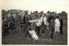 Impreza sob&oacute;tkowa w Pęgowie : w kapeluszu i okularach telereporter Pęgowskiej Kupalnocki z niezbędnym mobilnym sprzętem w postaci w&oacute;zka i teleskopu, 23.06.1984 r. [Dokument ikonograficzny]